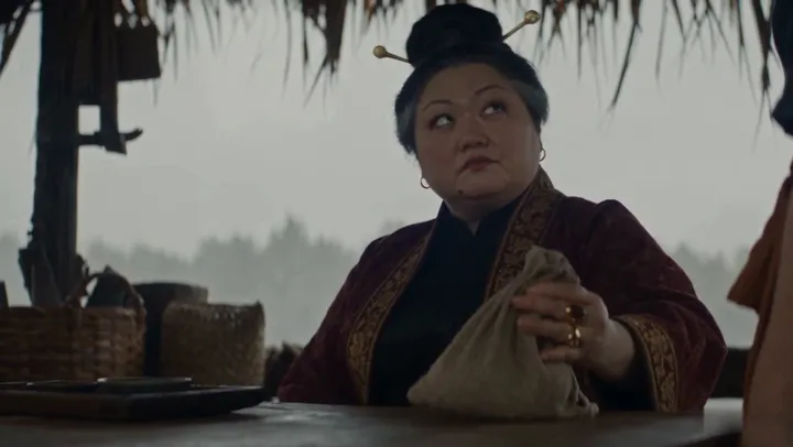 Madam Kora, the grain merchant, weighs a sack at her stall