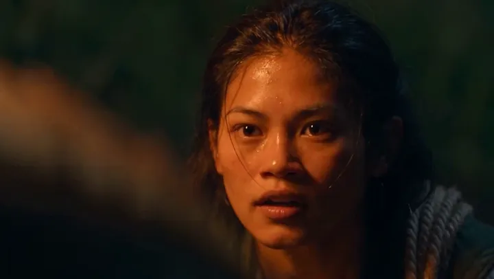 Close-up of Teva, her face lit by firelight